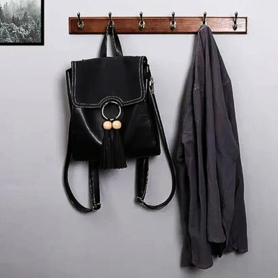 veste et sac suspendus sur porte manteau en bois vintage