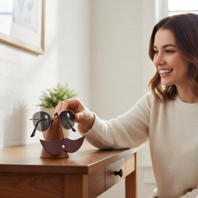 femme brune souriante pose lunettes sur porte lunettes moustaches