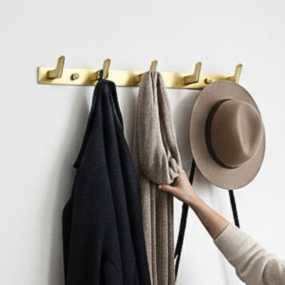 main prend écharpe sur porte manteaux doré cinq crochets