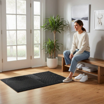 femme souriante enfile chaussures entrée maison tapis noir rainuré