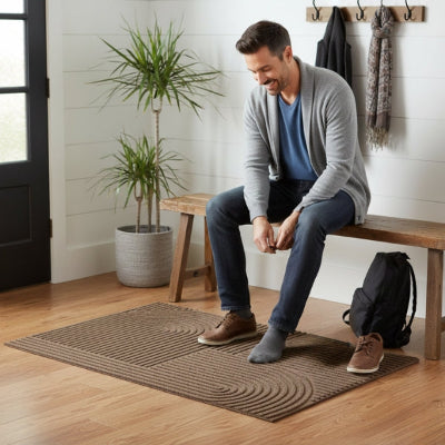 homme souriant enfiles chaussures sur tapis d'entrée absorbant noir rainuré arche