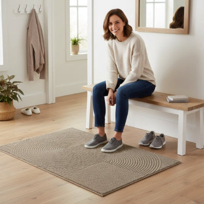 femme souriante enfile chaussures tapis d'entrée rainuré rond beige